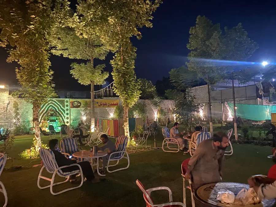 Guests dining in the lit garden at Safdar Hotel after dark